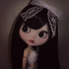 a doll with long black hair wearing a white dress