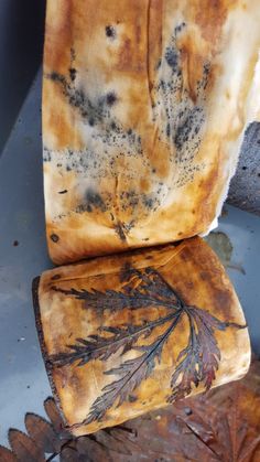 an old chair with leaves on the seat and rusted up leather covering it's back