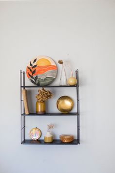 three black shelves with decorative items on them against a white wall in a living room