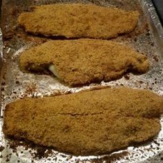 two pieces of fried fish sitting on top of a pan covered in seasoning powdered sugar