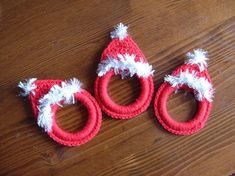 two crocheted red and white christmas hats sitting on top of a wooden table