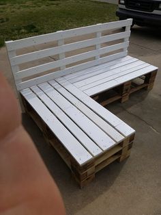 a bench made out of pallets sitting on the side of a road in front of a car