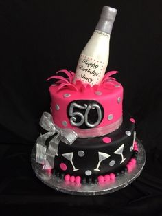 a 50th birthday cake with a bottle of wine on the top and polka dot design