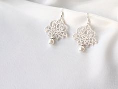 Minimalistic lace earrings with pearl will be an exclusive addition to your wedding look! These dangle tatting ivory earrings are very lightweight and comfortable to wear. MEASUREMENTS: earring height (minus ear wire): 4 cm earring total height (including ear wire): 5,5 cm earring width (widest point): 3 cm These earrings are ready to be shipped. Handmade Delicate Pearl White Bridal Earrings, Delicate Handmade Pearl White Bridal Earrings, Delicate Handmade White Chandelier Earrings, Handmade White Pearl Chandelier Earrings, Elegant Cream Beaded Earrings, Droplet Earrings, Ivory Earrings, Small Chandelier, Lace Earrings