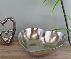 two heart shaped bowls sitting on top of a wooden table next to a potted plant