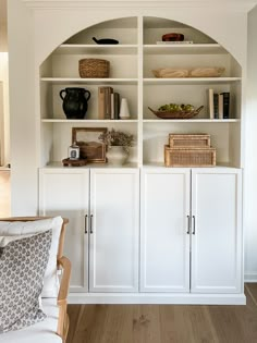 a living room with white bookcases filled with books and other items on top of them