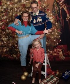 a man and woman pose for a photo in front of a christmas tree