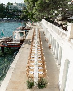 a long table is set up along the water's edge for an outdoor dinner