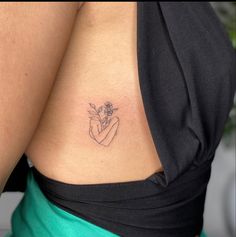 a woman's stomach with a small tattoo on her left side, holding a flower