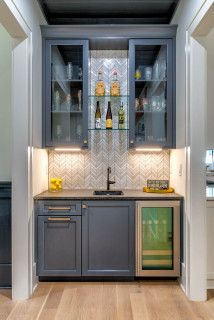 a kitchen with gray cabinets and wooden flooring next to a wall mounted wine rack