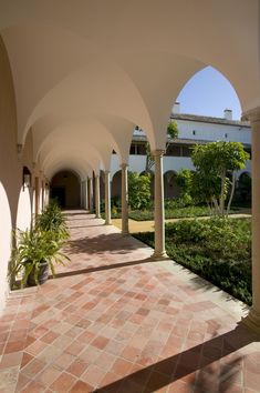 the walkway is lined with arches and potted plants