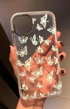 a woman's hand holding an iphone case with white butterflies on it