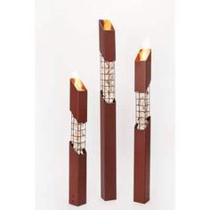 three tall candles are lit in the shape of squares and rectangles with glass panels on them