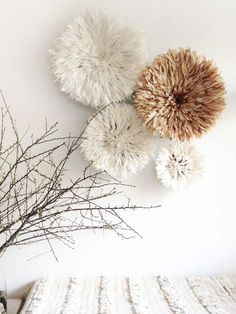 three white and brown pom - poms hang on the wall above a bed