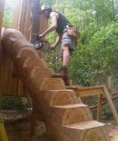 a man with a chainsaw working on a wooden structure in the woods