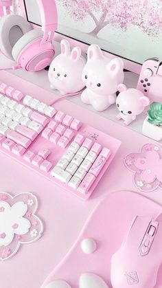 a pink keyboard and mouse on a desk with other items in front of the computer