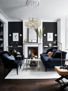 a living room filled with furniture and a fire place under a chandelier hanging from the ceiling