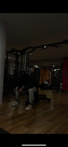 a person sitting on a bench in the middle of a gym with machines behind them