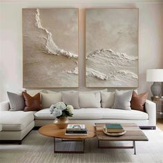 a living room with two large paintings on the wall and a coffee table in front of it