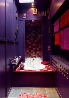 a bathroom with purple walls and tile flooring in the shower area, along with red towels hanging on the wall