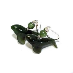 pair of green glass dolphin earrings on white background