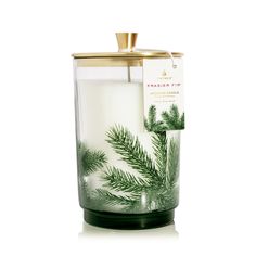 a candle that is sitting in front of a white background with green leaves on it