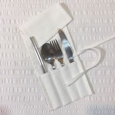 silverware and utensils are sitting in a pocket on a white tablecloth