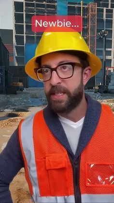 a man wearing a yellow hard hat and safety vest in front of construction site with newbie sign