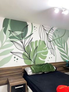 a bed sitting in front of a wall with leaves painted on it's side