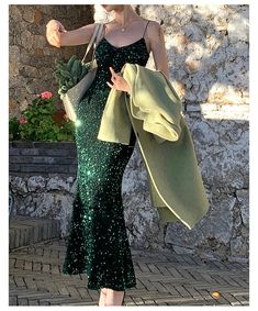 a woman in a green sequined dress is holding an umbrella