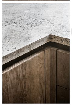 a kitchen counter top with wooden cabinets and white marble on the edges, is shown in this image