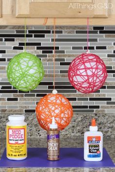 yarn ball ornaments hanging from the kitchen counter with glue and other crafting supplies around them