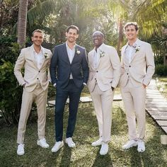 three men in suits and white shoes standing next to each other with palm trees behind them