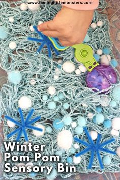 an image of someones hand holding a string pom pom toy in front of snowflakes