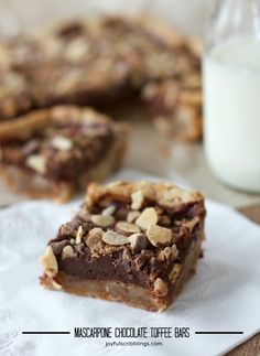 chocolate toffee bars with almonds on top and milk in the back ground