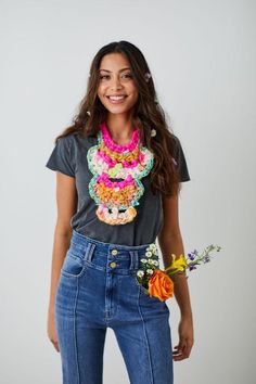 a young woman is smiling and holding a flower in her left hand while wearing a t - shirt with an image of a llama on it