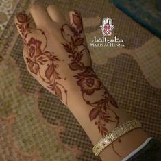 a woman's hand with henna on it and gold bracelet around her wrist