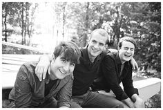 three young men are posing for a black and white photo in front of some trees