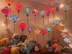 many colorful lanterns hanging from the ceiling in a room filled with pillows and other items