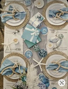 the table is set with blue and white plates, napkins, and seashells