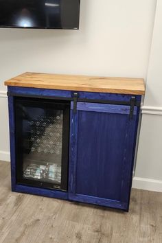 a television mounted on the wall next to a blue cabinet with glass doors and wooden top