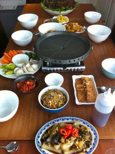 a wooden table topped with plates and bowls filled with different types of food on top of it