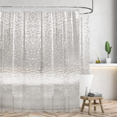 a white shower curtain in a bathroom next to a wooden stool and potted plant