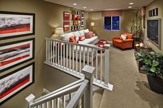 a living room filled with furniture and pictures on the wall next to a stair case