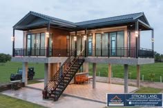 a two story house sitting on top of a lush green field next to a metal staircase