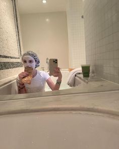 a woman taking a selfie in the bathroom while wearing a towel on her head