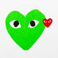 a green heart with two eyes and a red heart on the left side, in front of a white t - shirt that says i love you