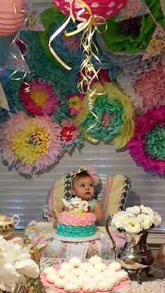 a baby sitting in a highchair next to a cake