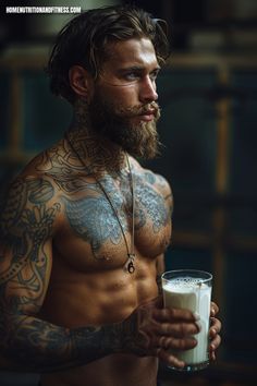 a man with tattoos holding a glass of milk