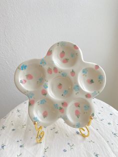 a white plate with pink and blue flowers on it sitting on top of a table